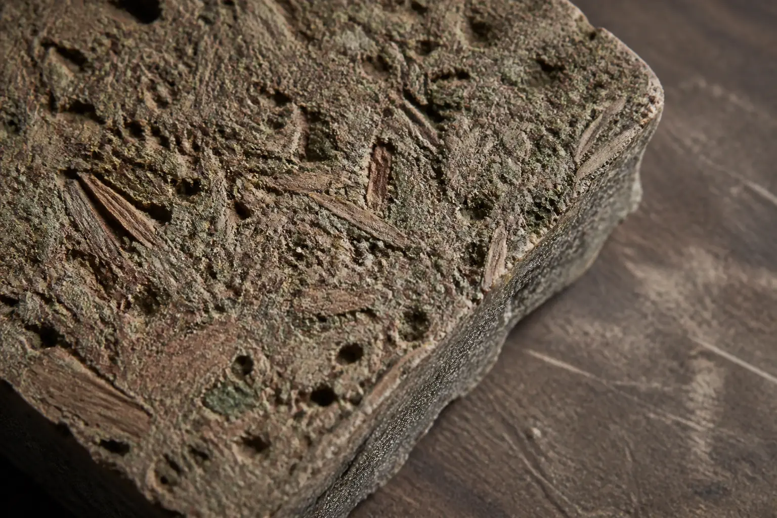 Échantillon de beton de bois brut, gros plan macro sur copeaux, liant minéral et texture poreuse en atelier