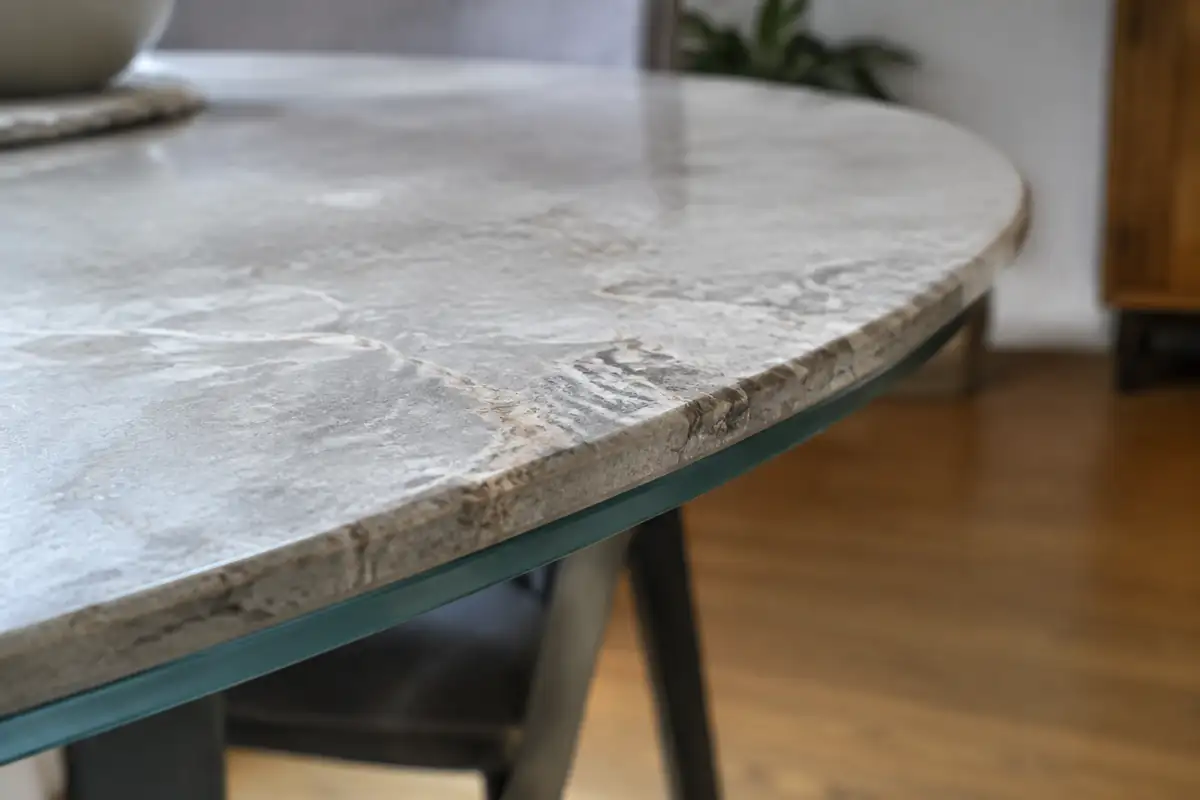 Bord arrondi d'un plateau de table en céramique effet pierre, collé sur son support en verre