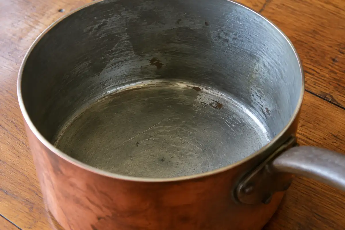 Intérieur gris d'une casserole en cuivre étamée, avec de fines rayures sur le revêtement